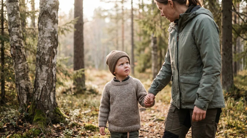 barn der holder sin mors hånd og ser bekymret ud i en skov